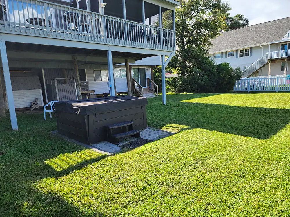 Maintained backyard lawn around a hot tub and raised deck