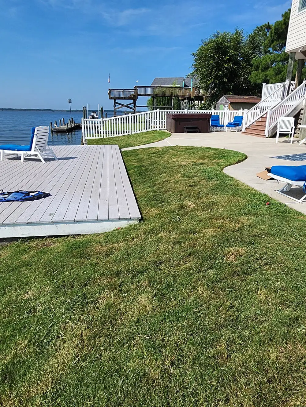 Maintained waterfront backyard lawn beside a patio and deck